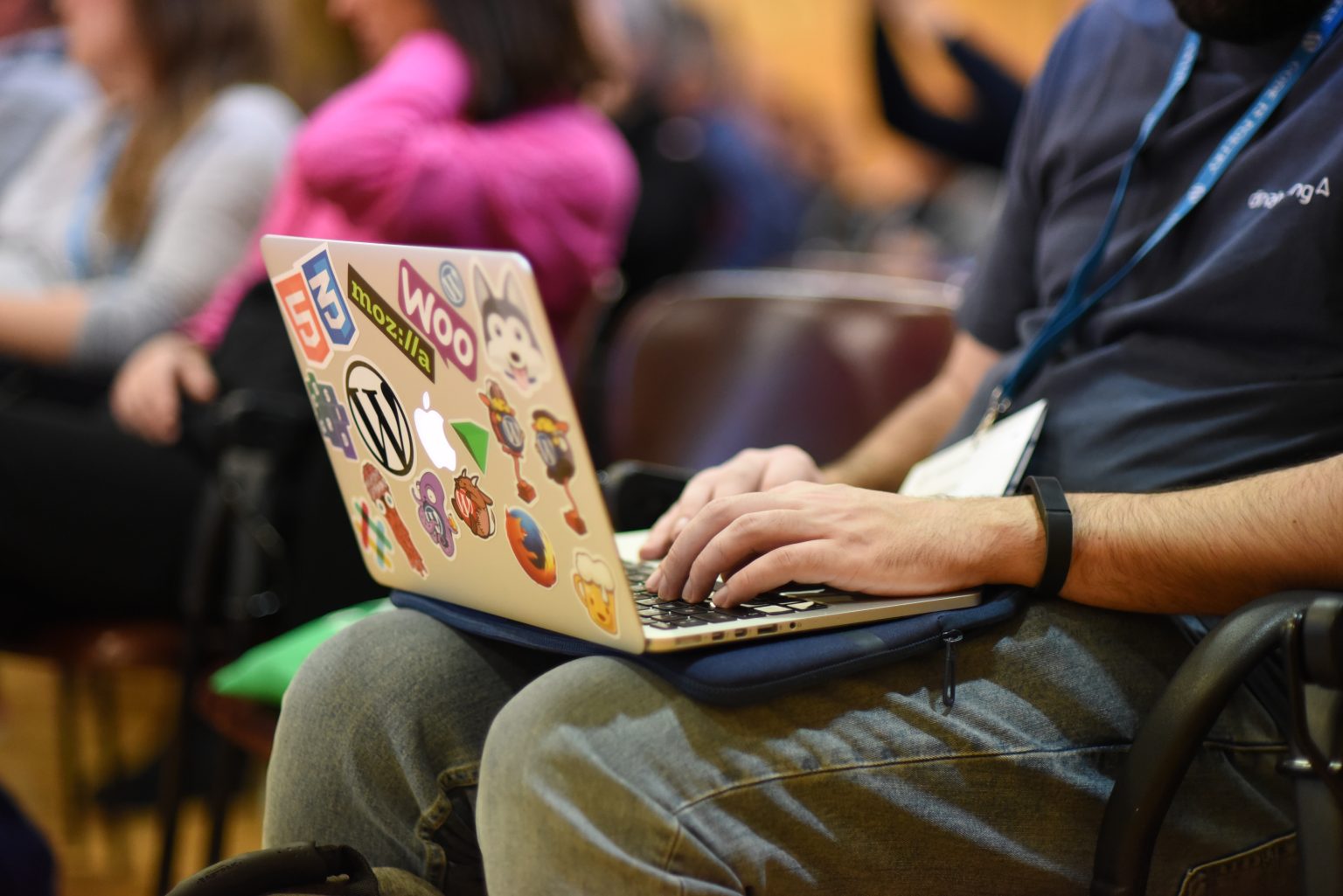 Person taking notes on a laptop at a community event